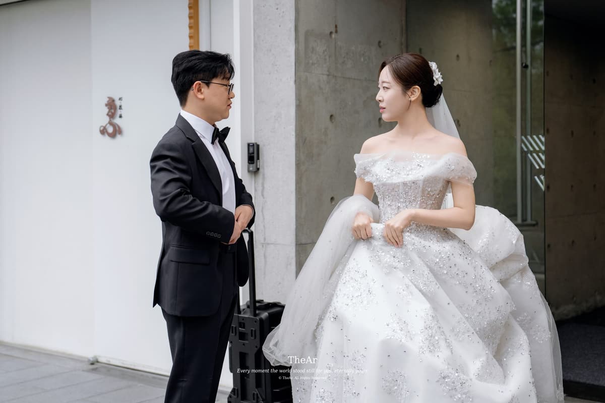 메이크업샵 건물 앞에 나와 드레스 자락을 들고 신랑과 마주 선 신부
