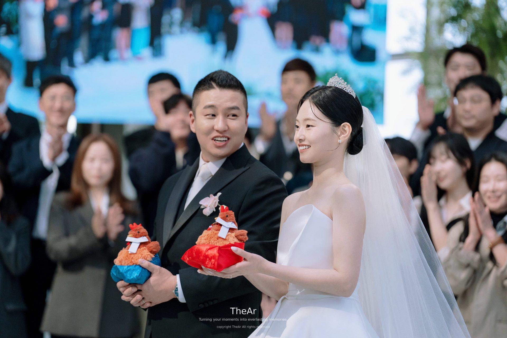 하객들 앞에서 축하 인형을 받아 든 신랑과 신부