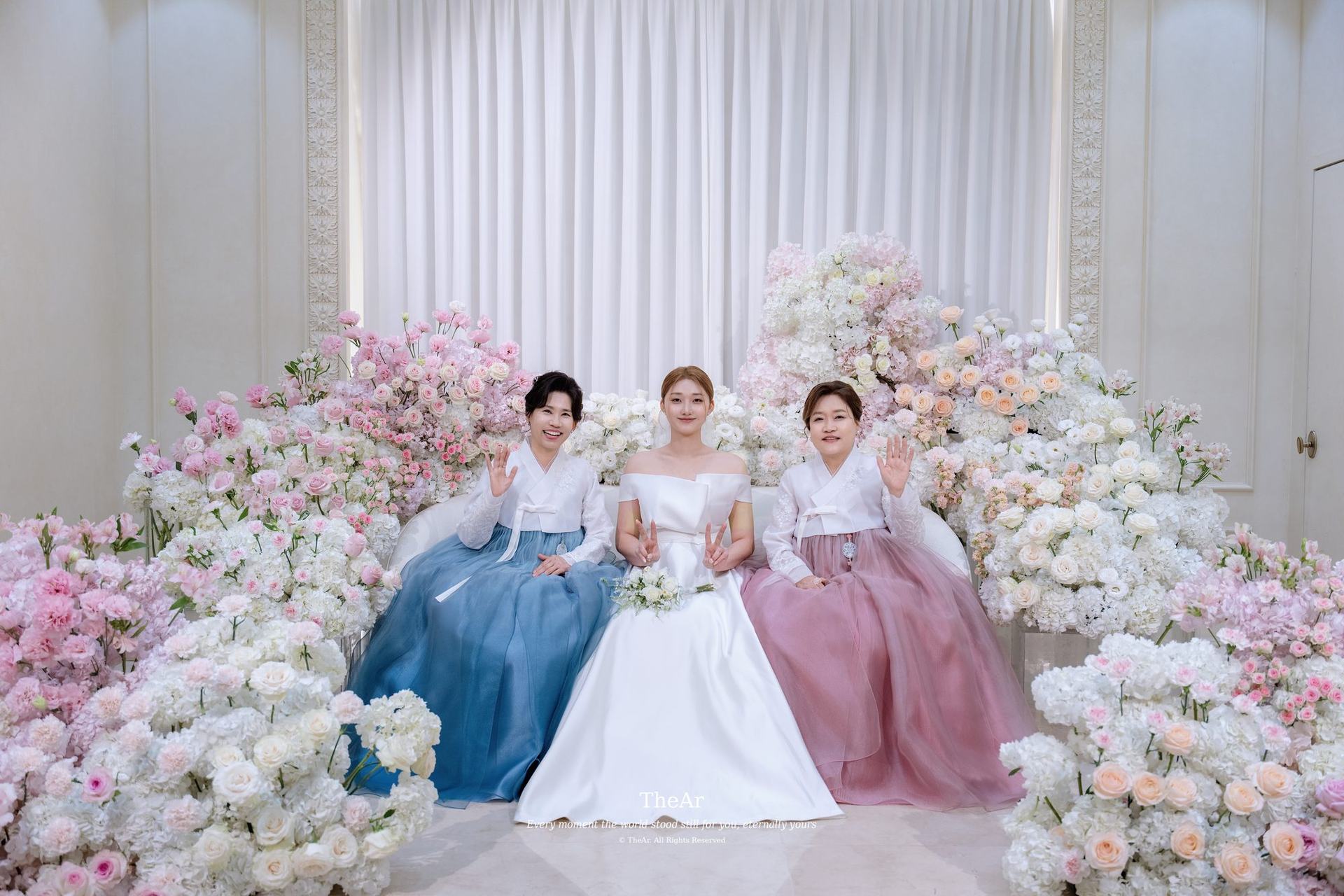 꽃 포토월 앞에 친구들과 앉은 신부